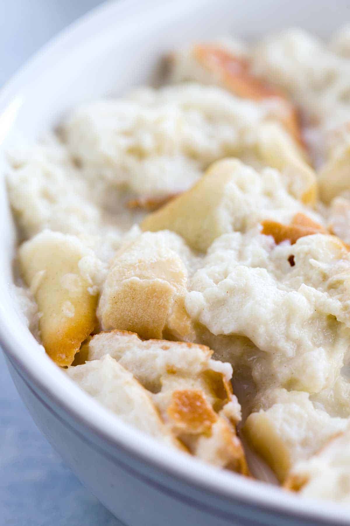 A bowl of pieces of bread soaking in milk.