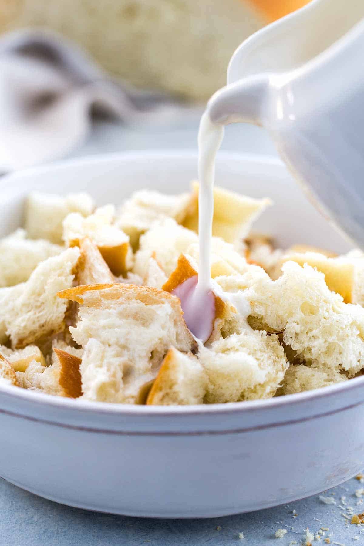 Milk being poured into a bowl of bread pieces.