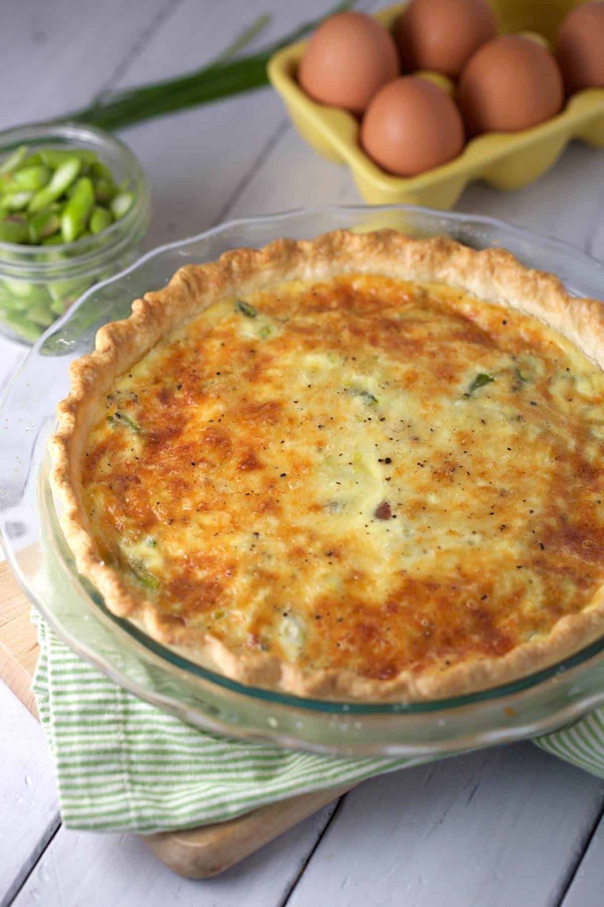 Ham and asparagus quiche in a glass pie plate.