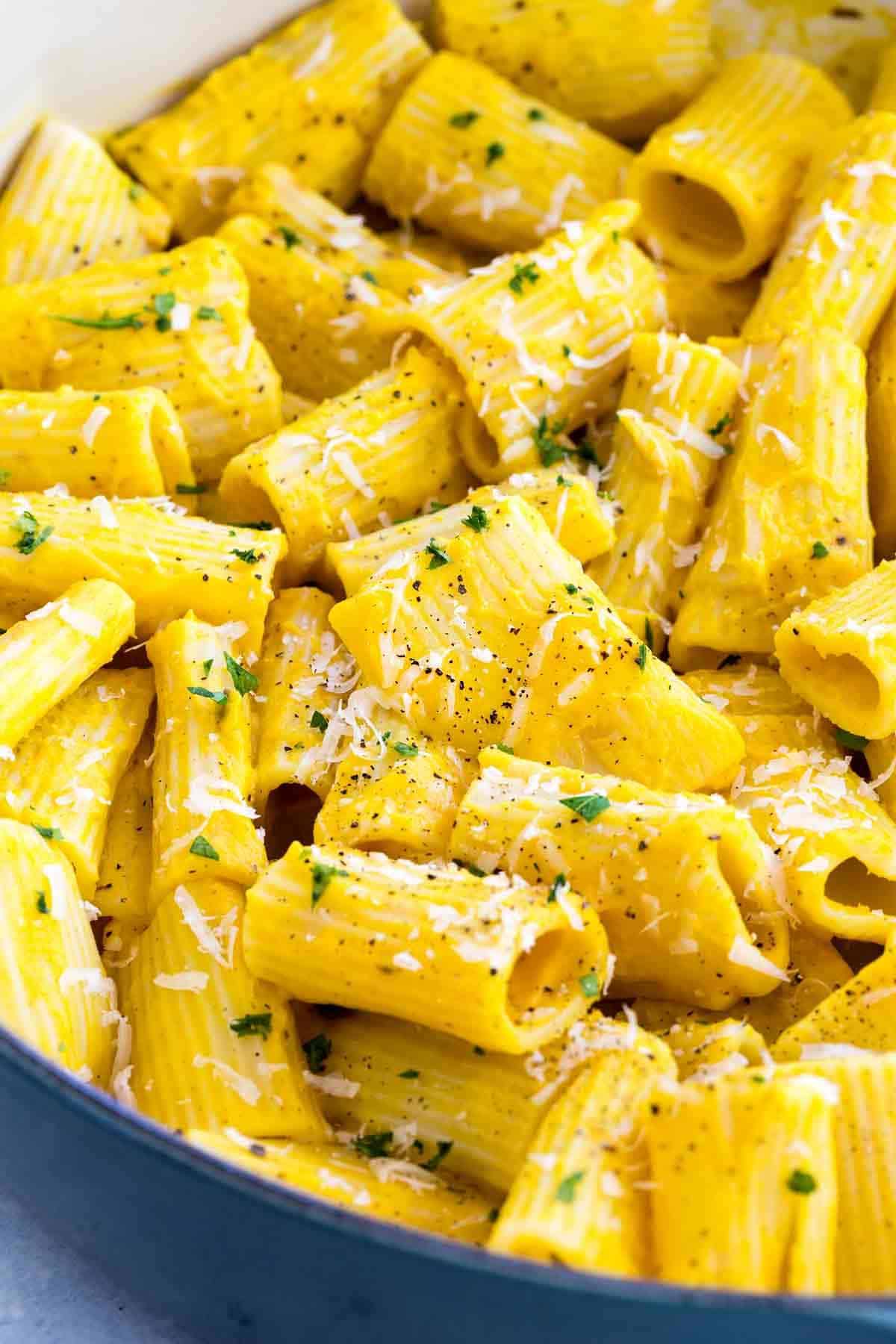 Rigatoni coated in creamy yellow butternut squash sauce, sprinkled with shredded Parmesan, black pepper, and fresh parsley.