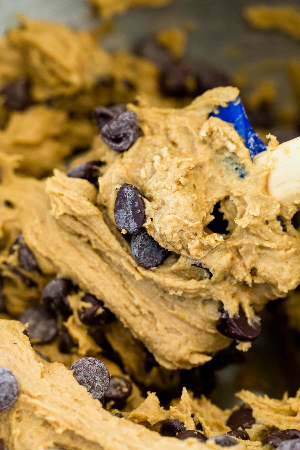 Spatula mixing chocolate chip cookies dough in a bowl.