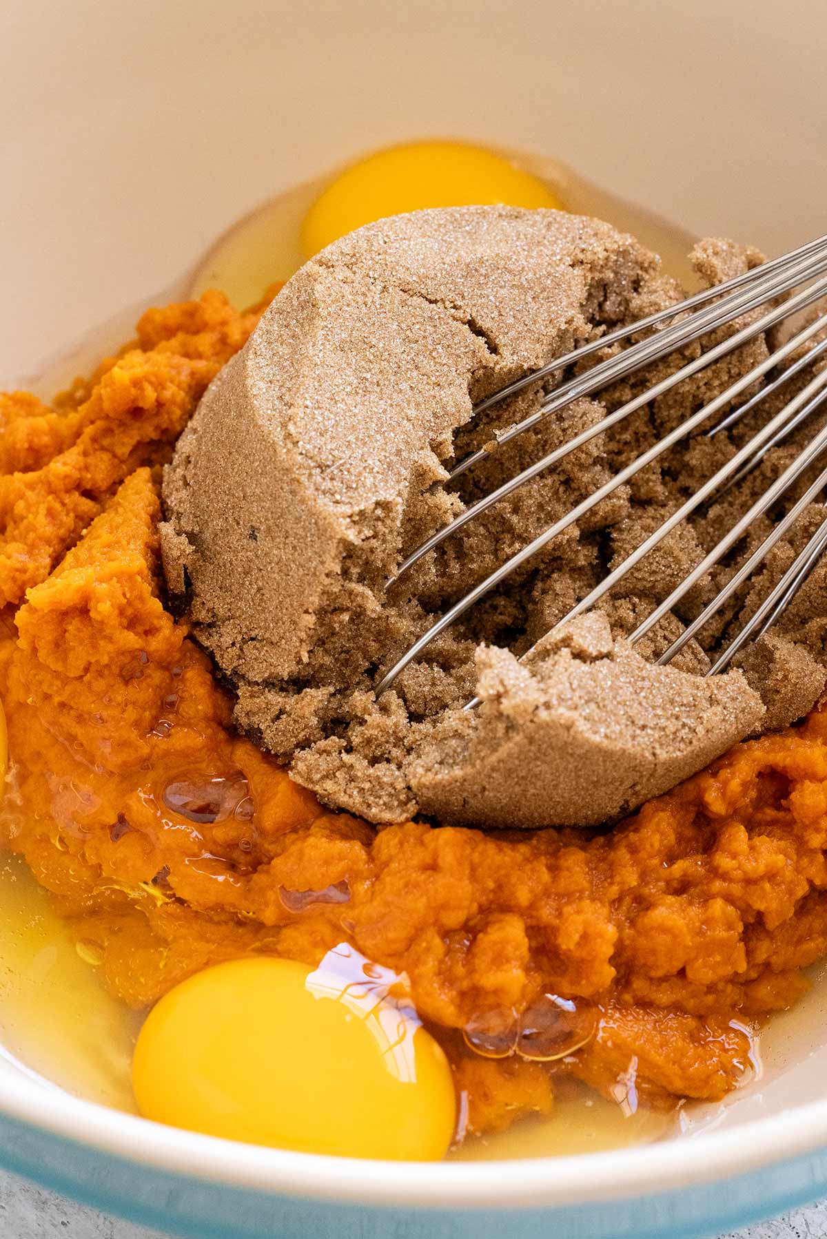 Brown sugar, eggs, and pumpkin puree in a bowl.