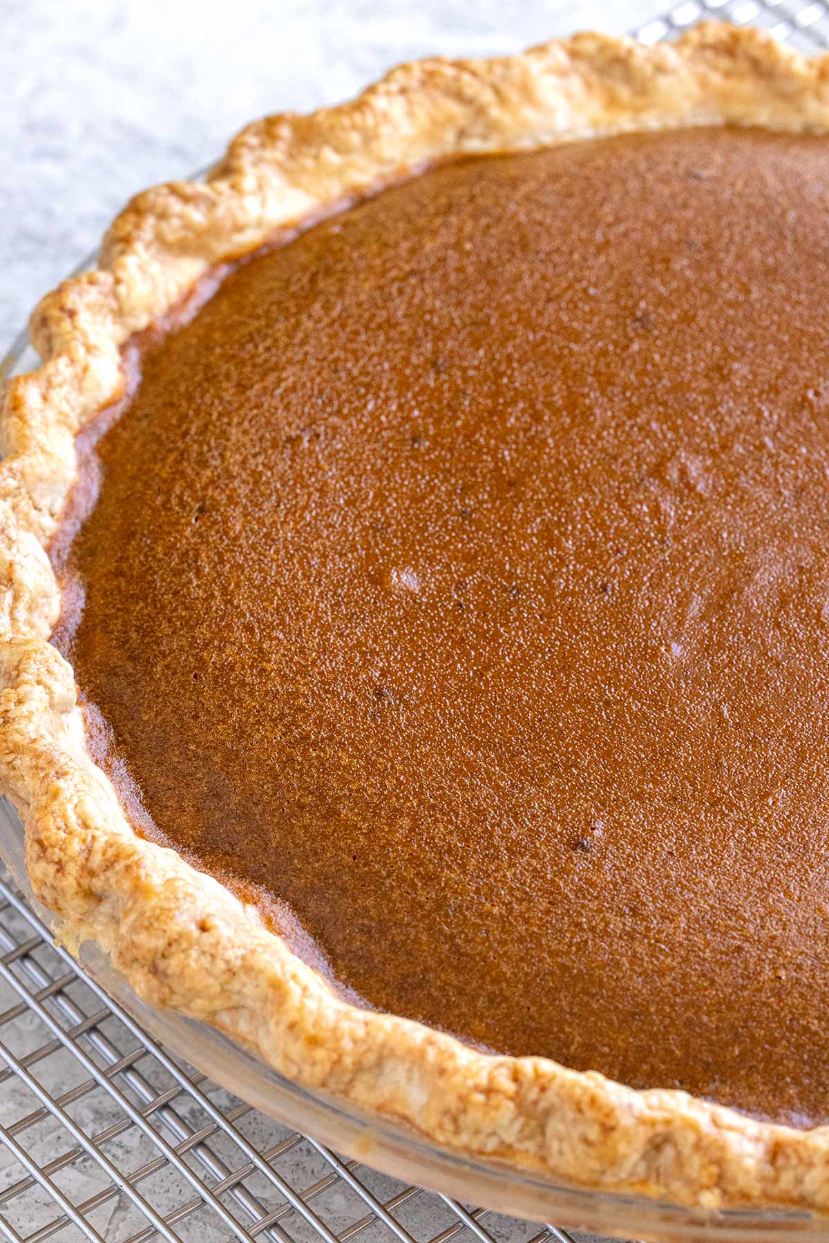 Freshly baked pumpkin pie cooling on a wire rack.