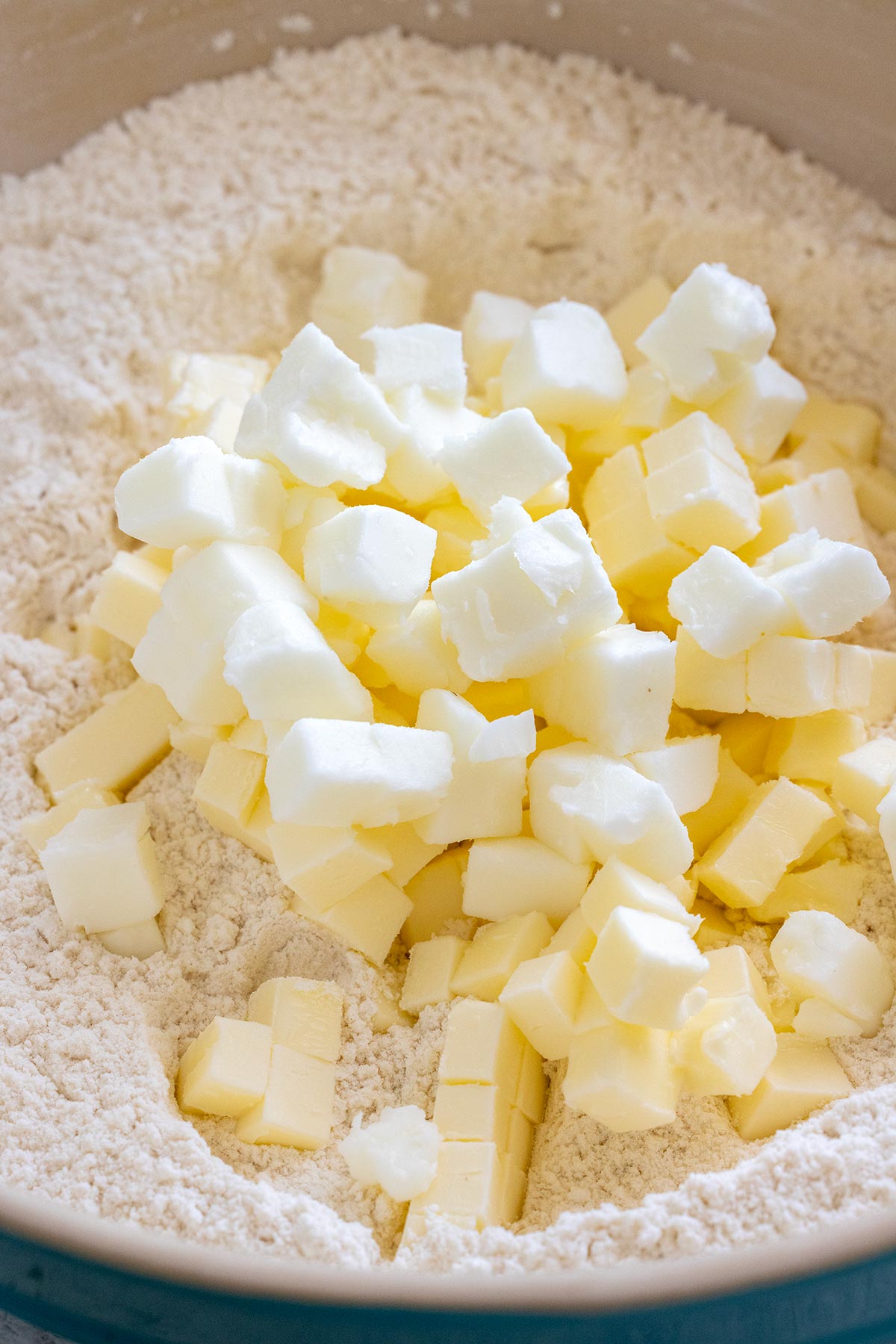 Cubes of butter and shortening in a bowl of flour.