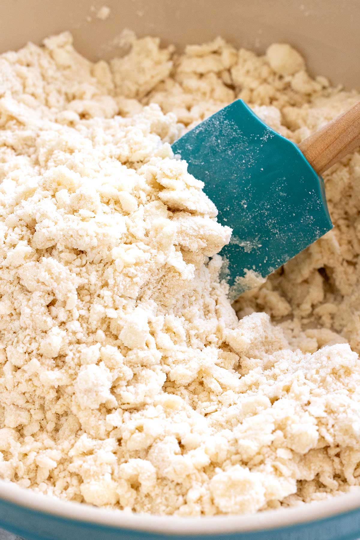 Spatula mixing a pie dough crust in a bowl.