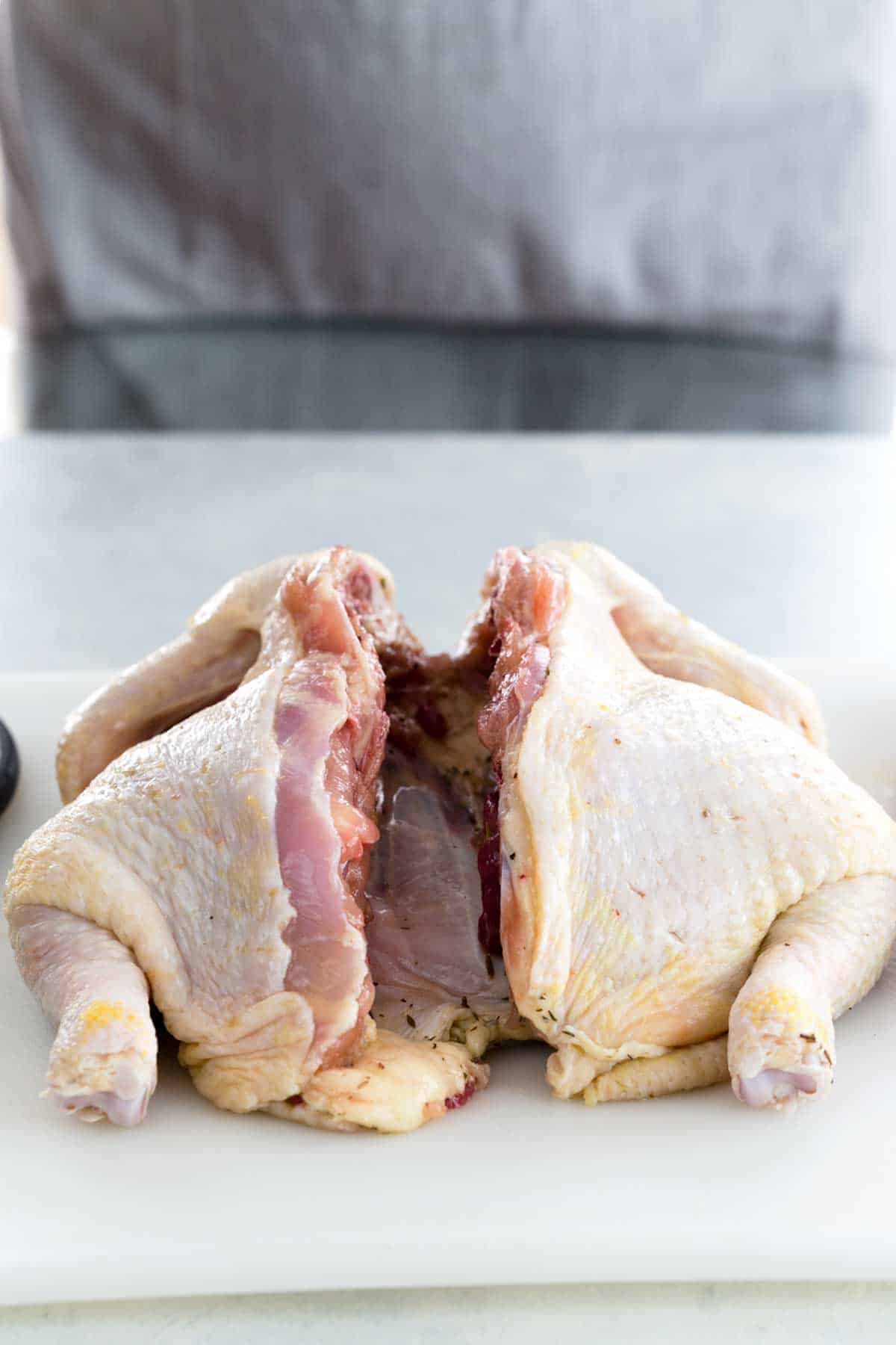 Whole chicken on a cutting board with backbone removed.