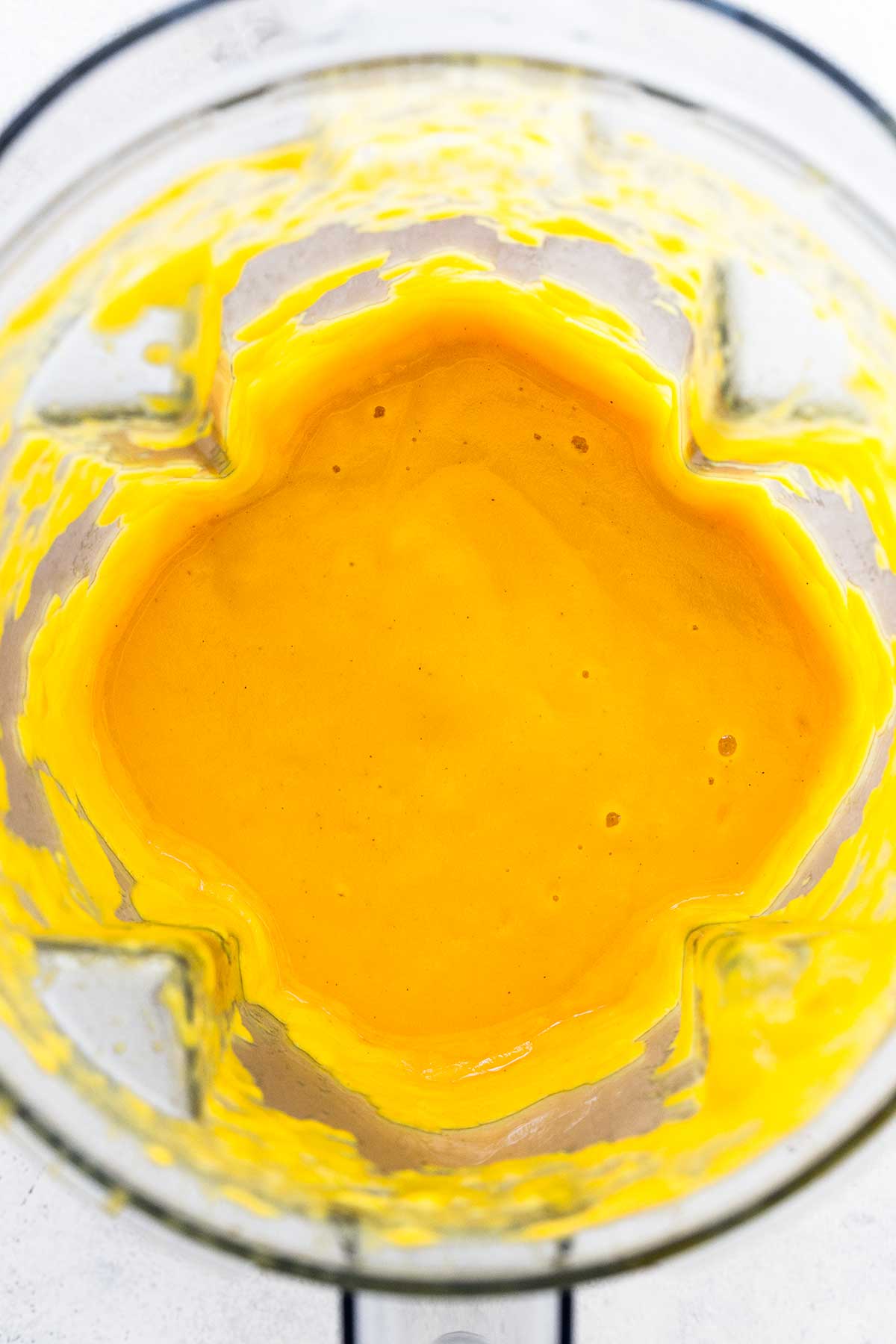 Smooth, bright orange puréed butternut squash sauce inside a blender jar.