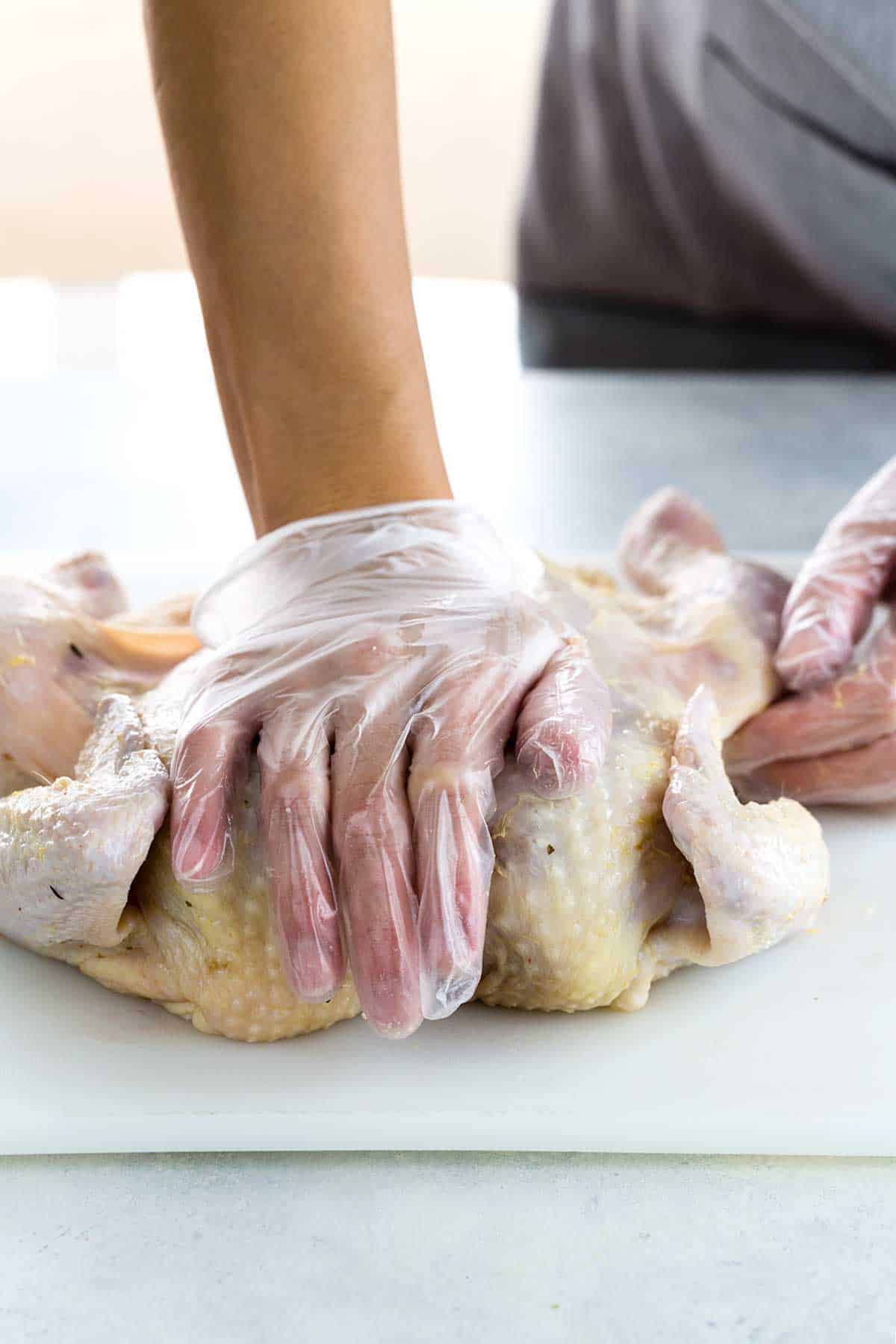 Hand pressing against chicken to spread the surface area of the meat.