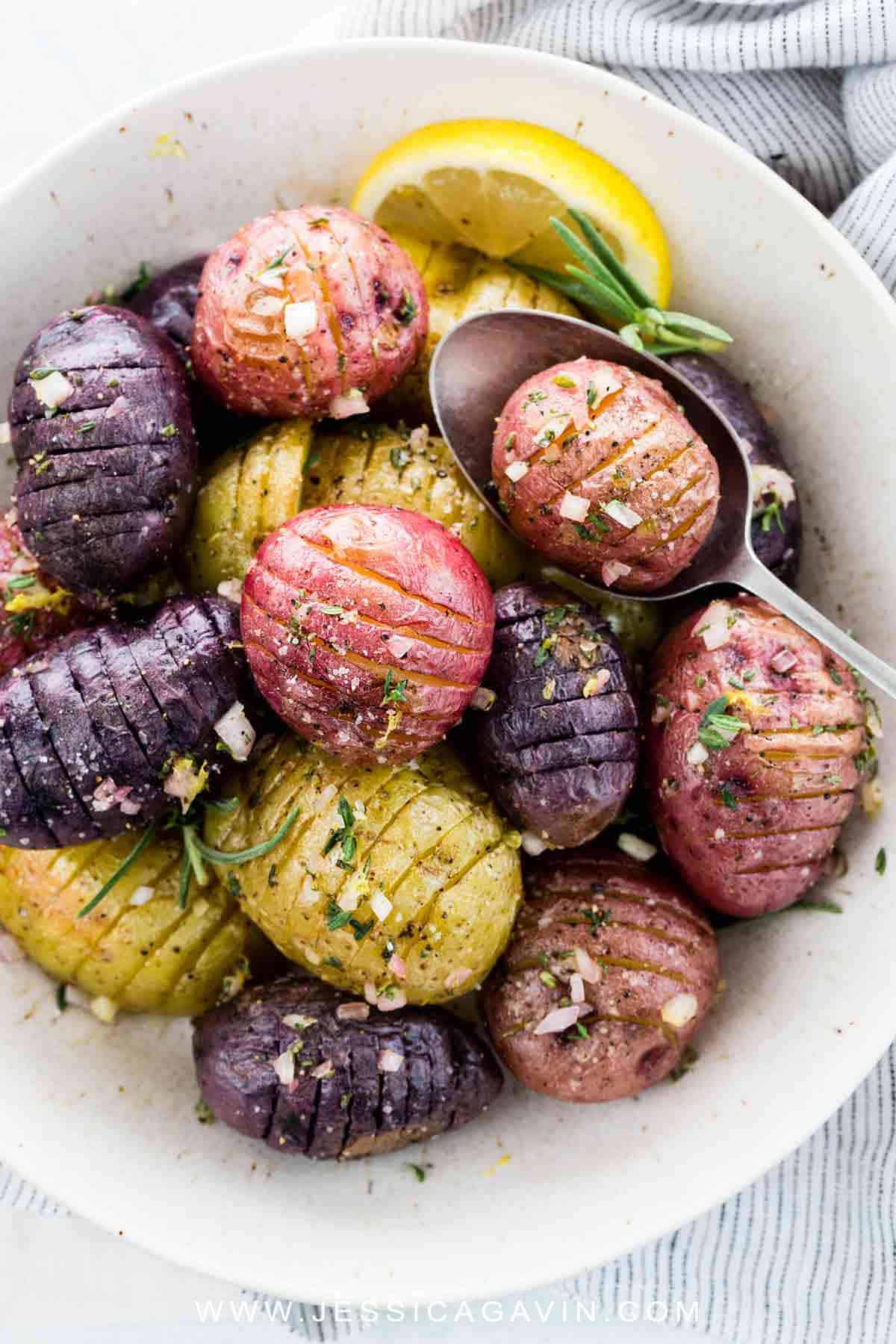 Hasselback potatoes roasted until crisp and topped with a tangy lemon garlic sauce. A flavorful and wholesome side dish bursting with fresh herbs and seasonings. #sidedish #potatoes #hasselback #vegan #whole30
