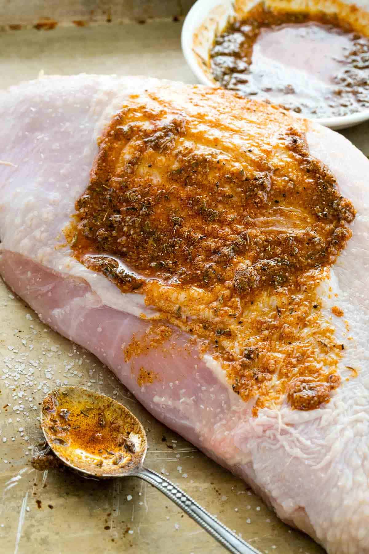 spreading a spice rub over a turkey breast