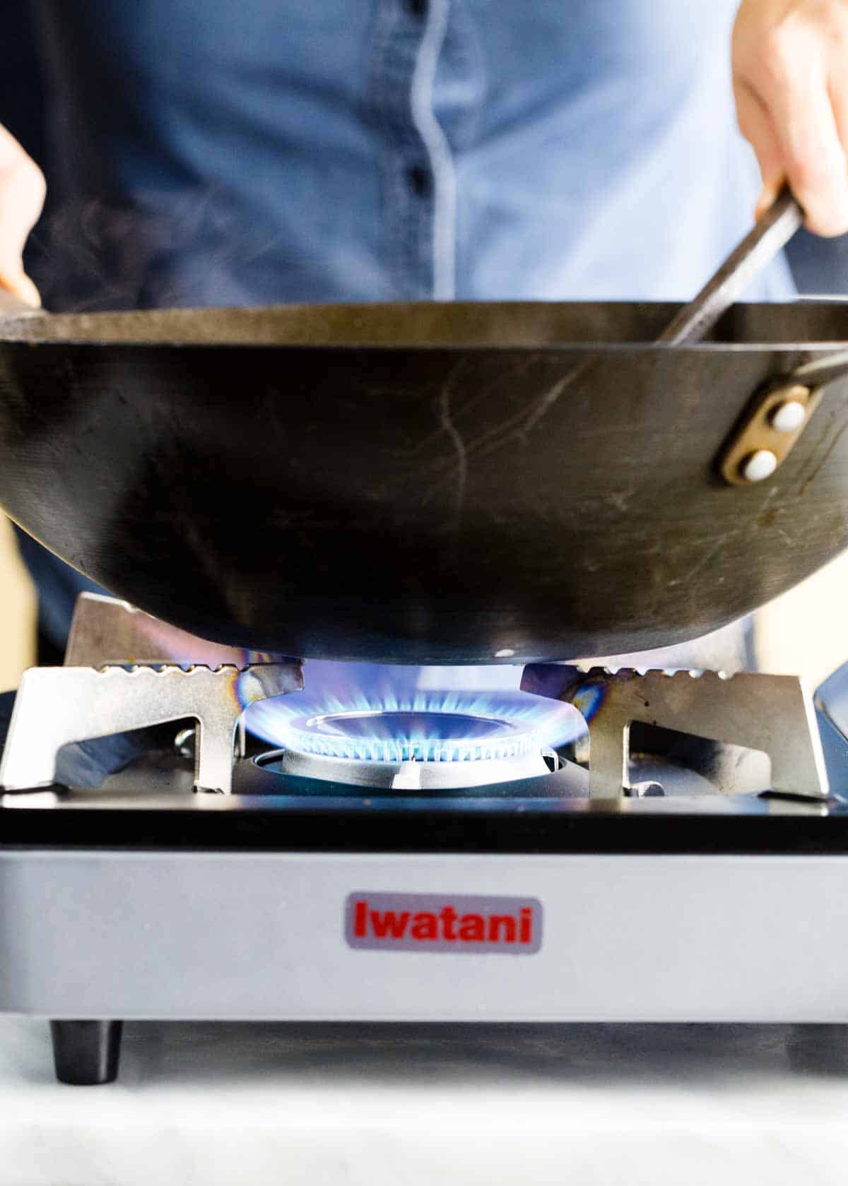 Side photo showing flames from a stove underneath a wok.