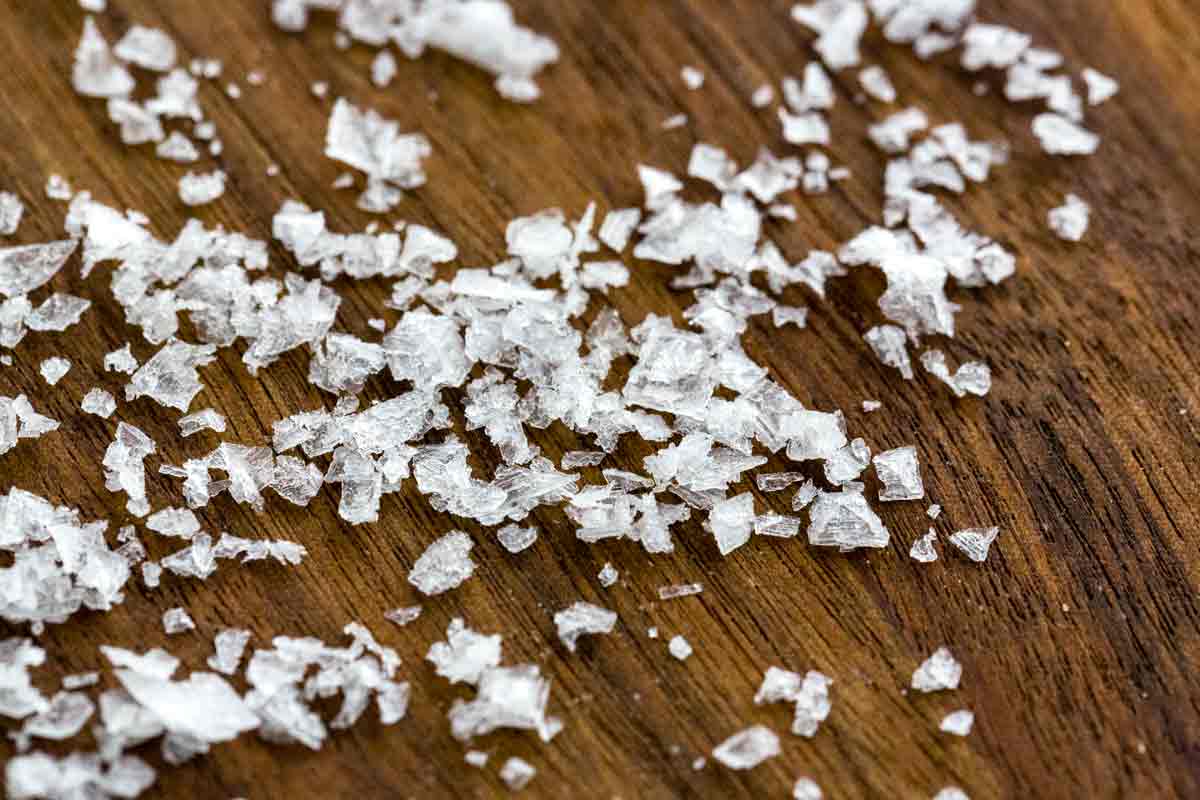 Flake sea salt spread across a wooden table.