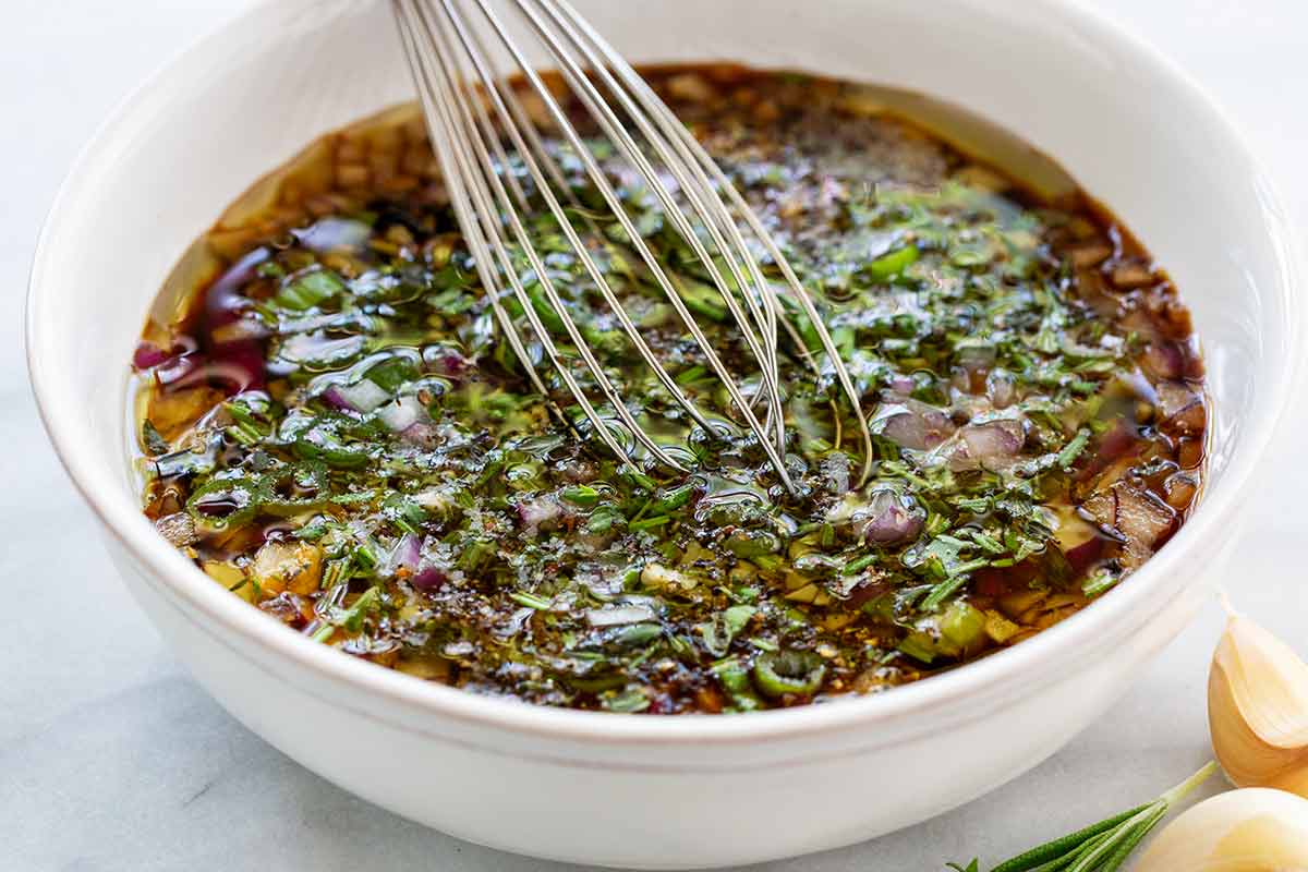 Steak marinade ingredients whisked together in a white bowl.