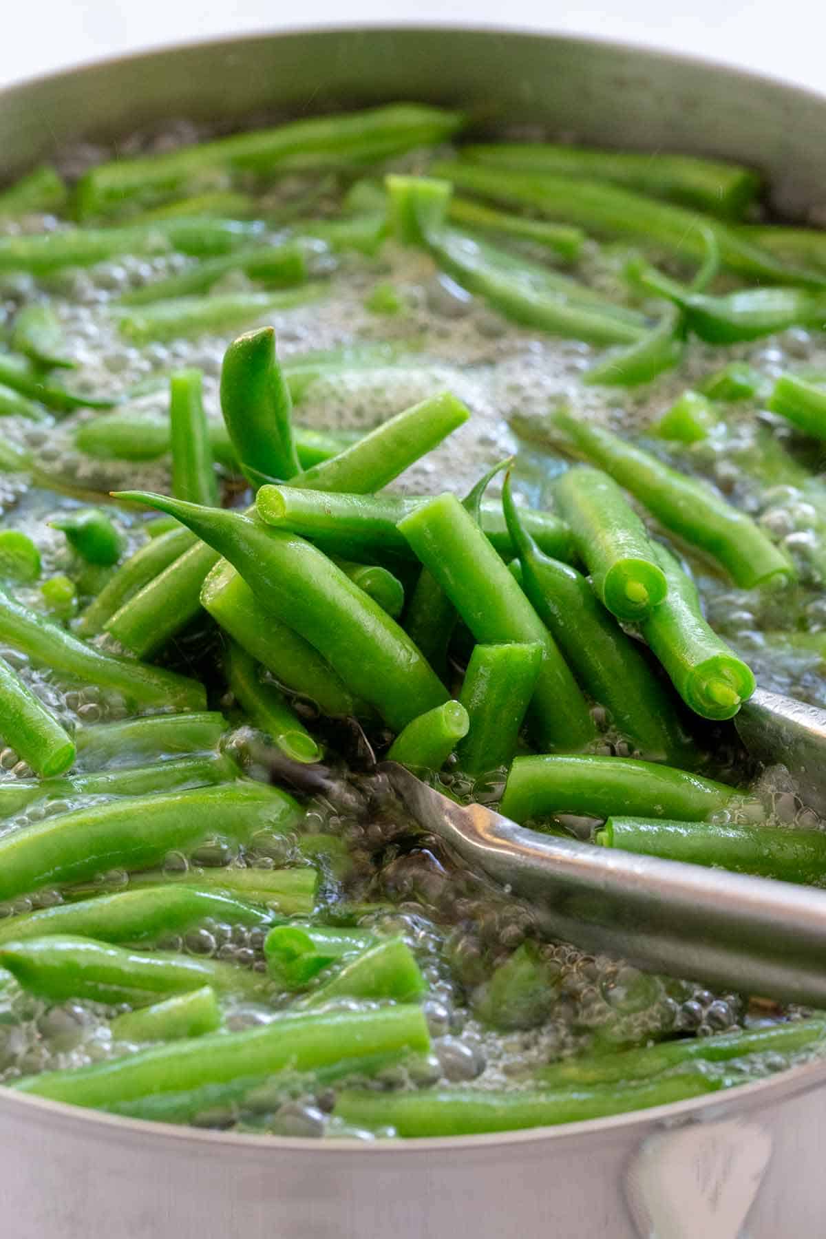 Green beans cooking in a boiling pot of water.