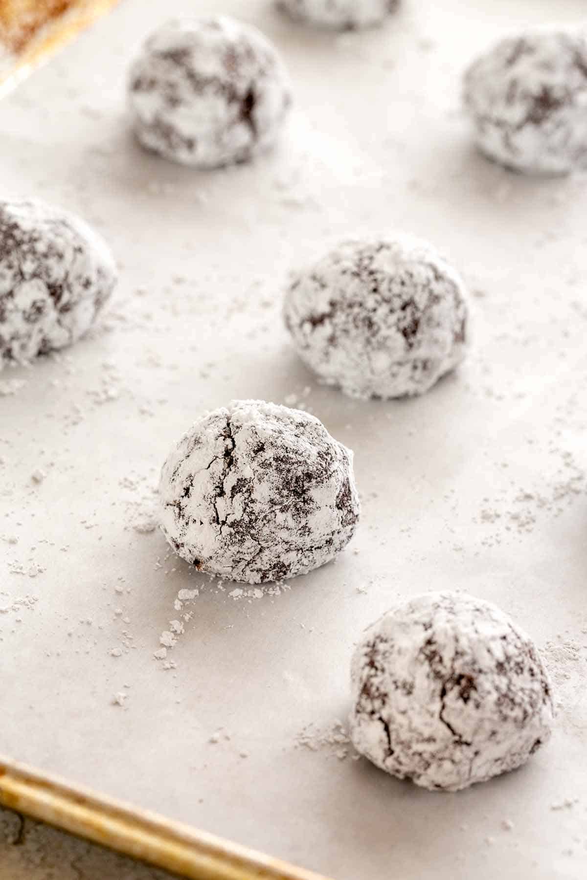 Round sugar coated cookie dough balls on a sheet pan-lined with parchment paper.