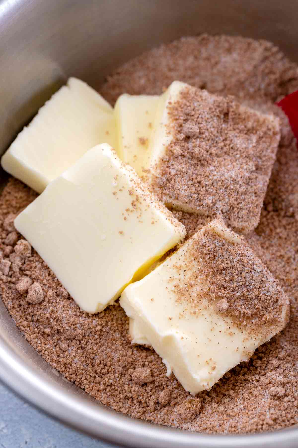 Slices of butter in a bowl with brown sugar.