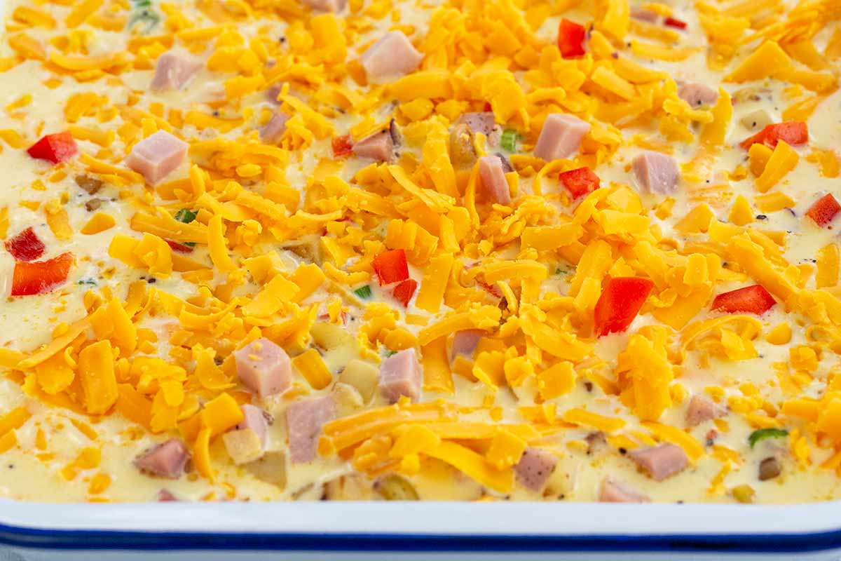 Casserole dish filled with liquid mixture and cheese.