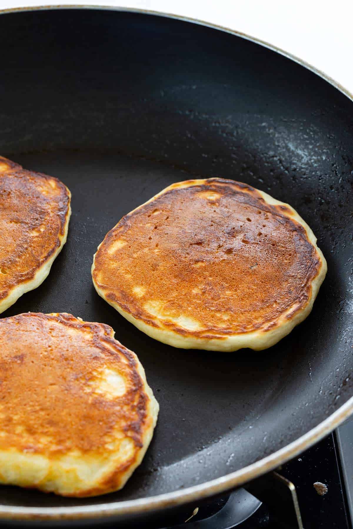 Pancakes cooking in a nonstick pan.