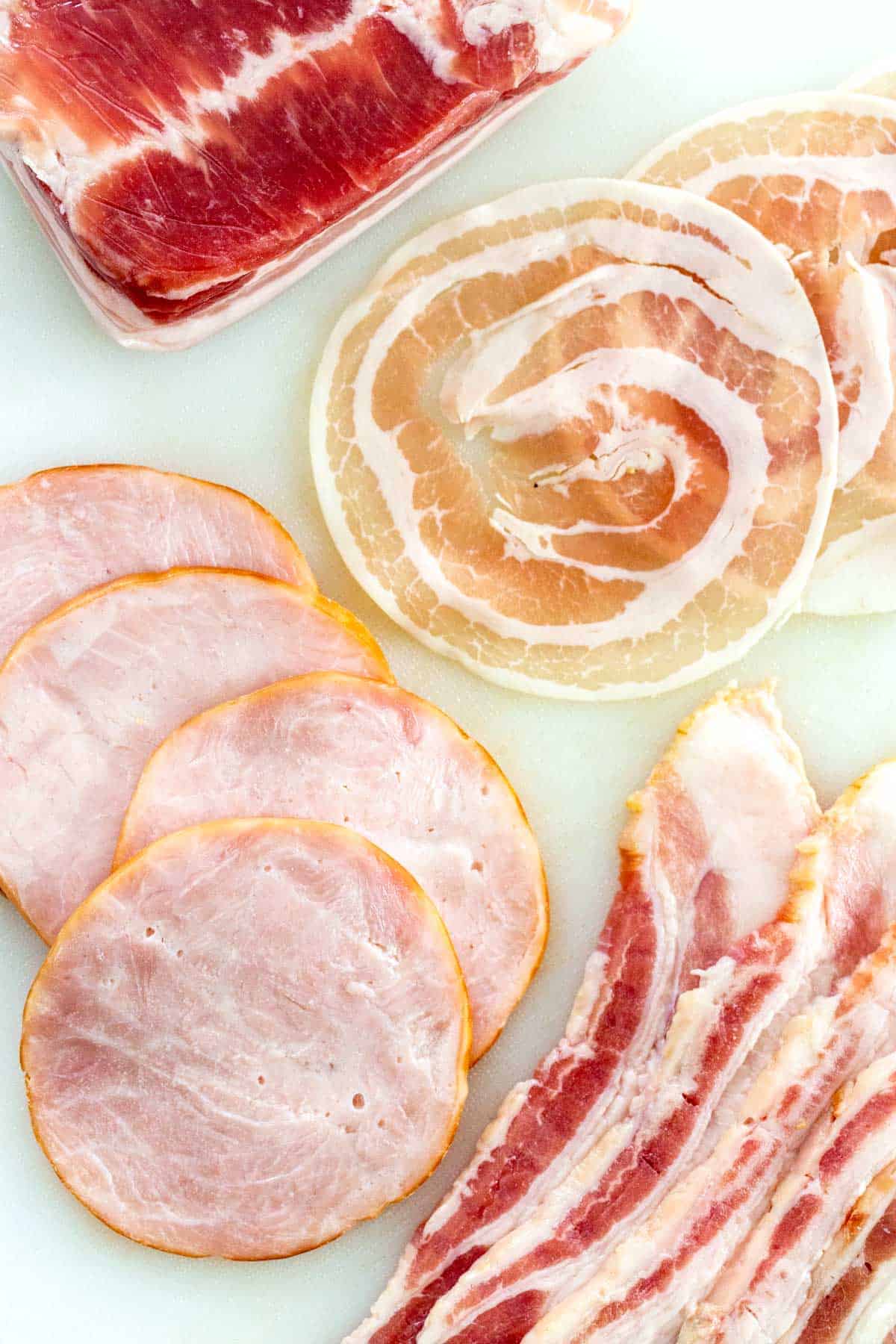 Different types of bacon spread across a cutting board.