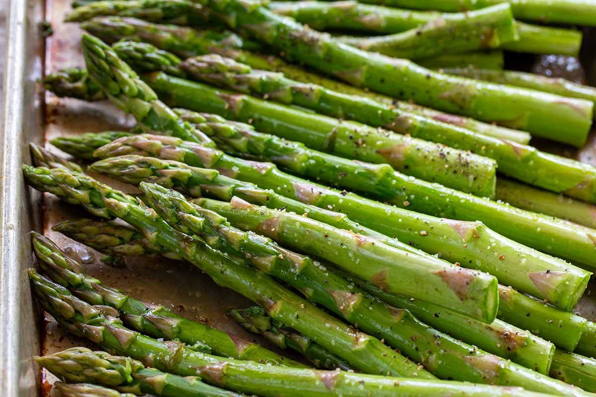 Seasoned asparagus spears on a sheet pan.