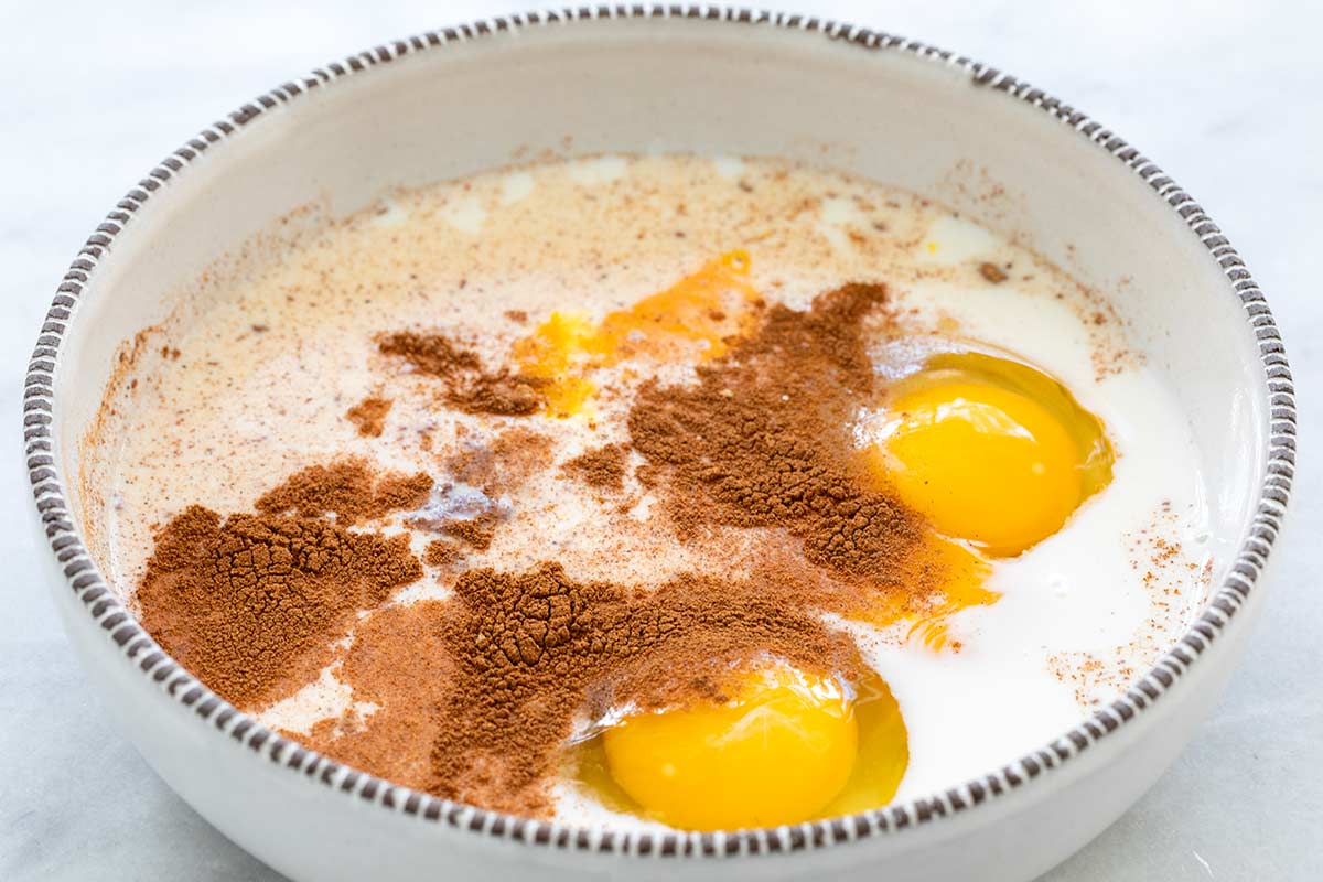 Eggs, milk, nutmeg, and brown sugar in a bowl.