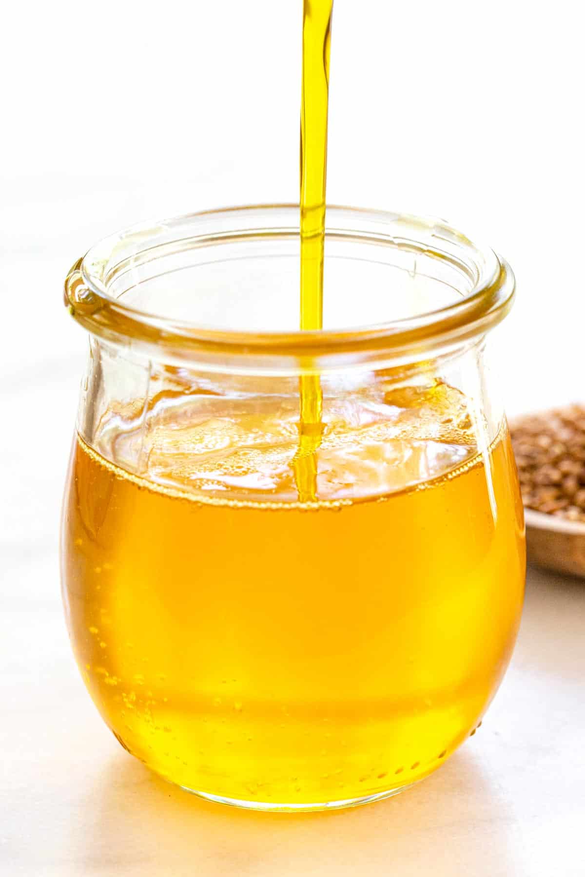 Pouring flaxseed oil into a glass jar.