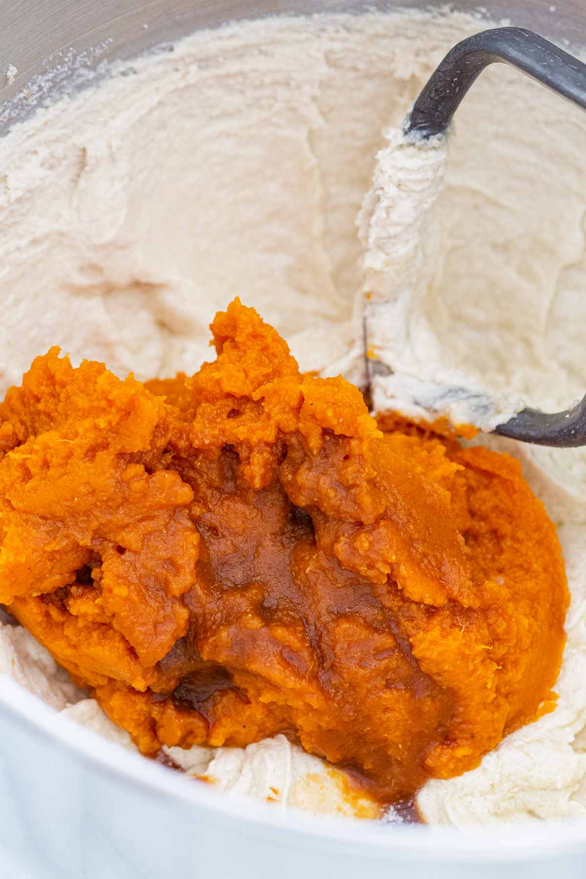 Scoop of pumpkin puree and vanilla in a mixer bowl.