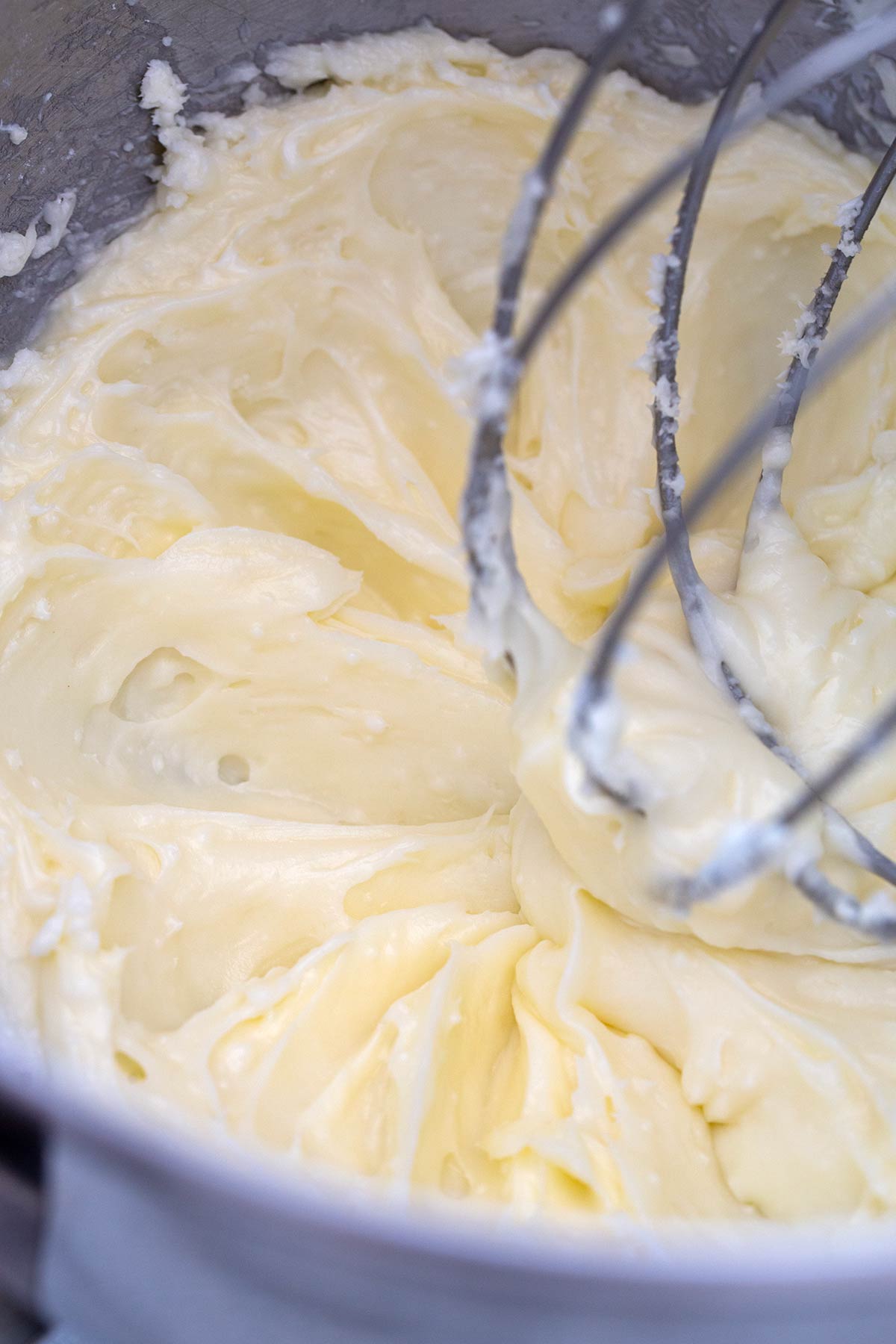 Butter and powdered sugar being whisked in a stand mixer bowl.