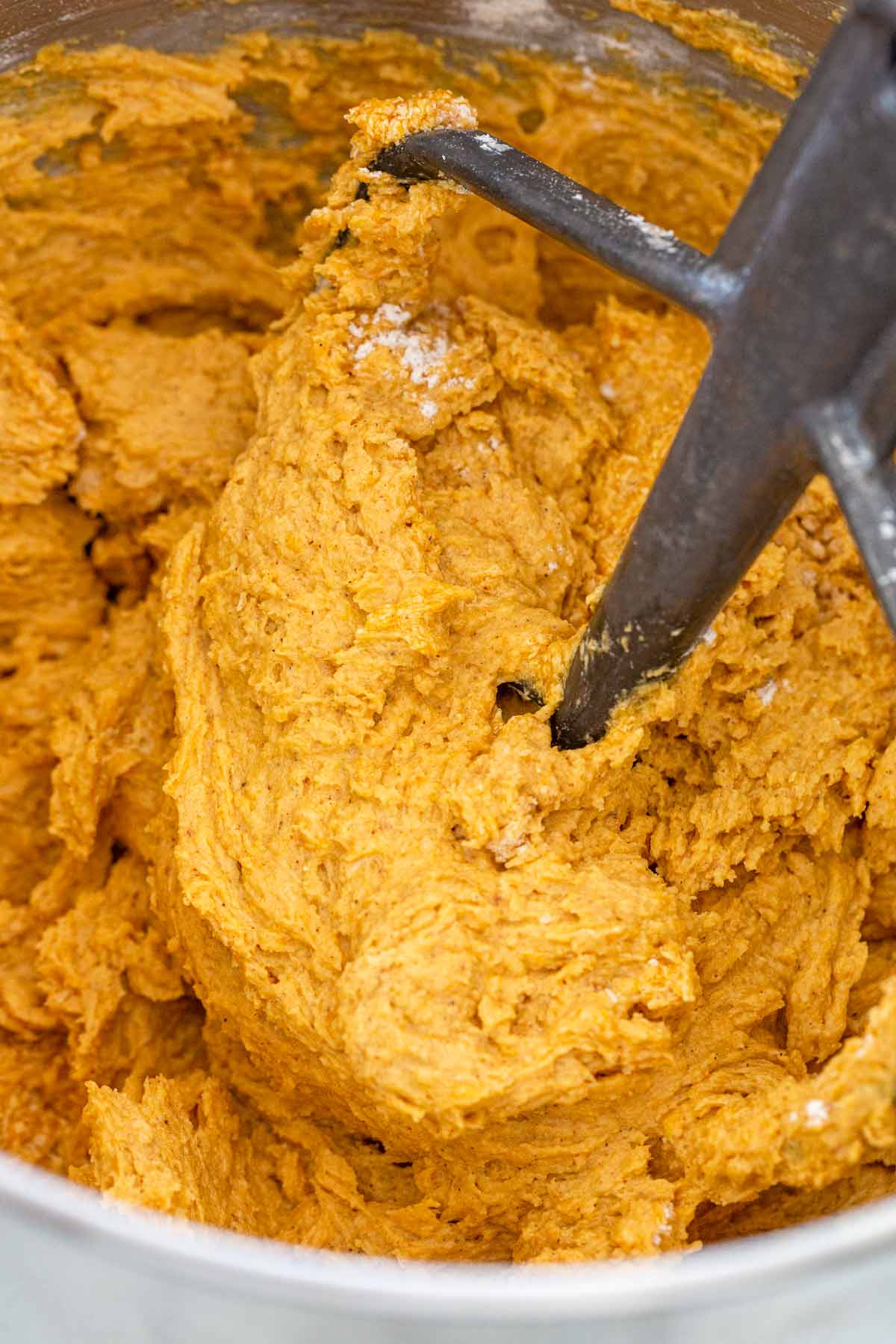 Pumpkin cookie dough being formed in a stand mixer.