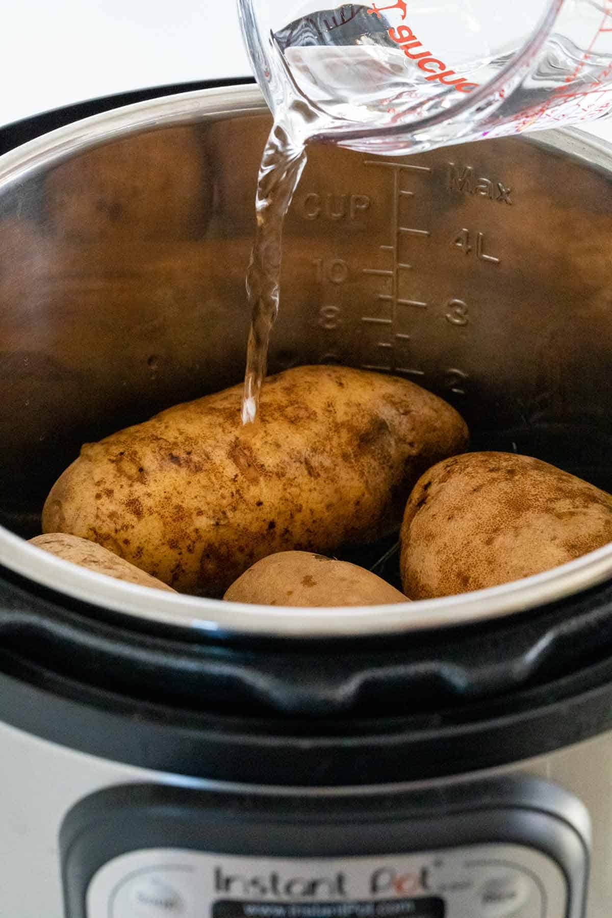 Adding water to an Instant Pot filled with Russet potatoes.