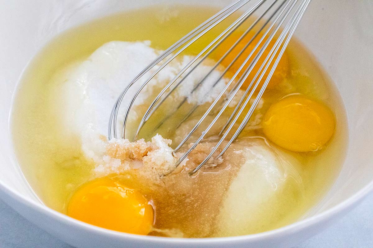 Eggs, sugar, and butter being whisked in a bowl.