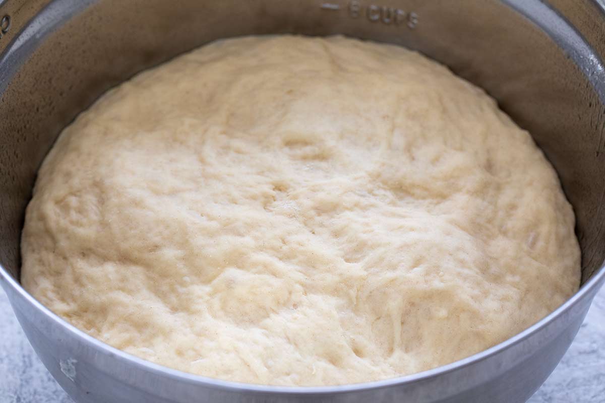Proofed dough in a metal mixing bowl.