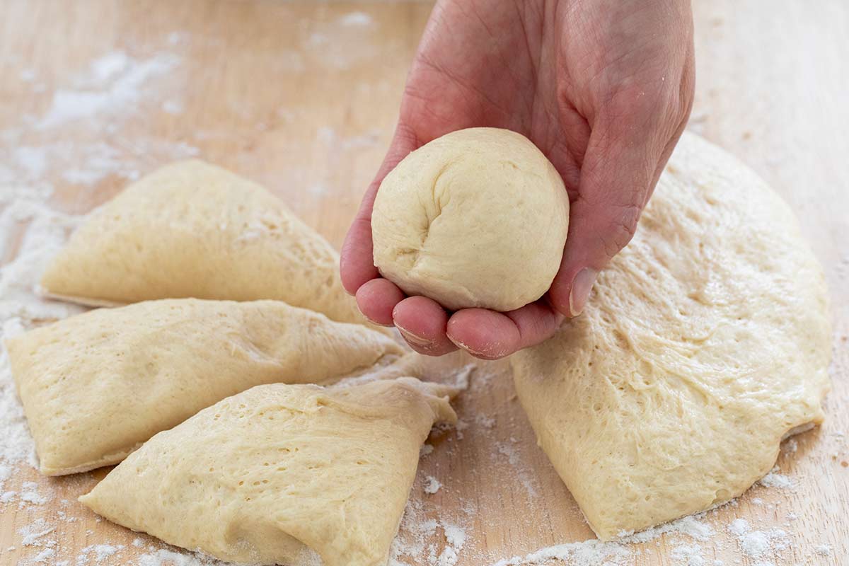 A hand holding a round dough ball.