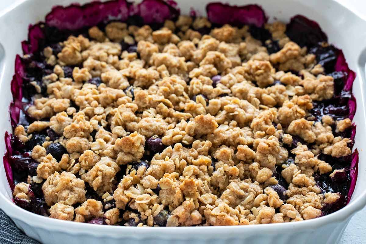 Baking dish with blueberry on the sides and crunchy oats on top.