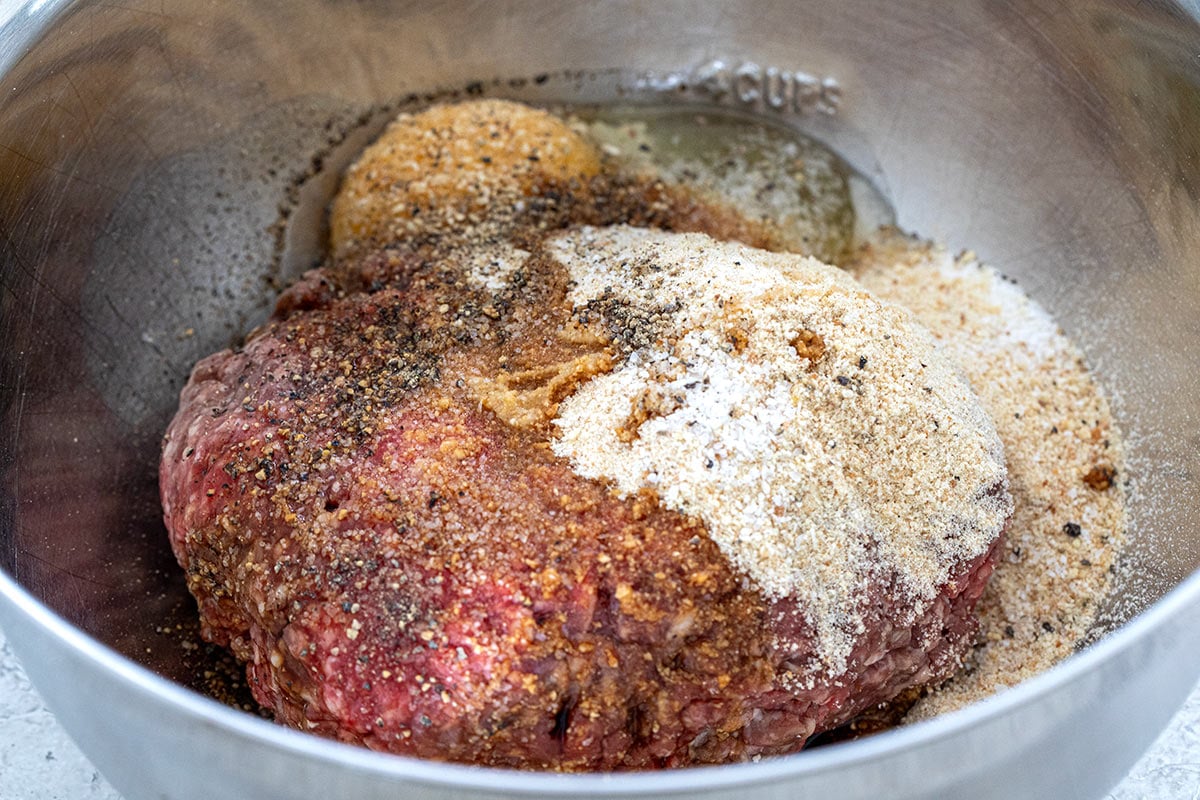 Ground beef, breadcrumbs, and seasoning in a mixing bowl.