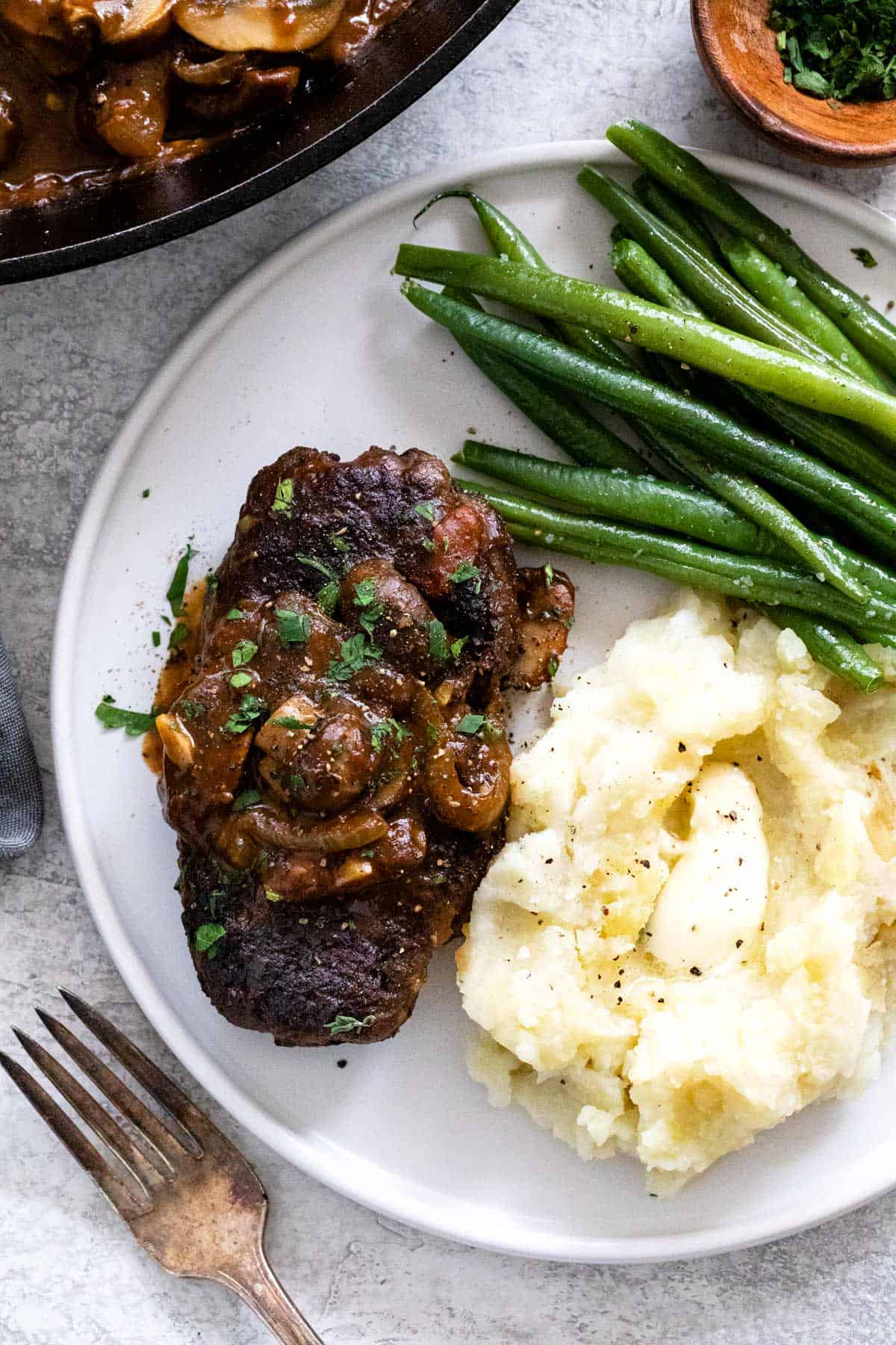 Plate of salisbury steak with mashed potatoes and green beans.