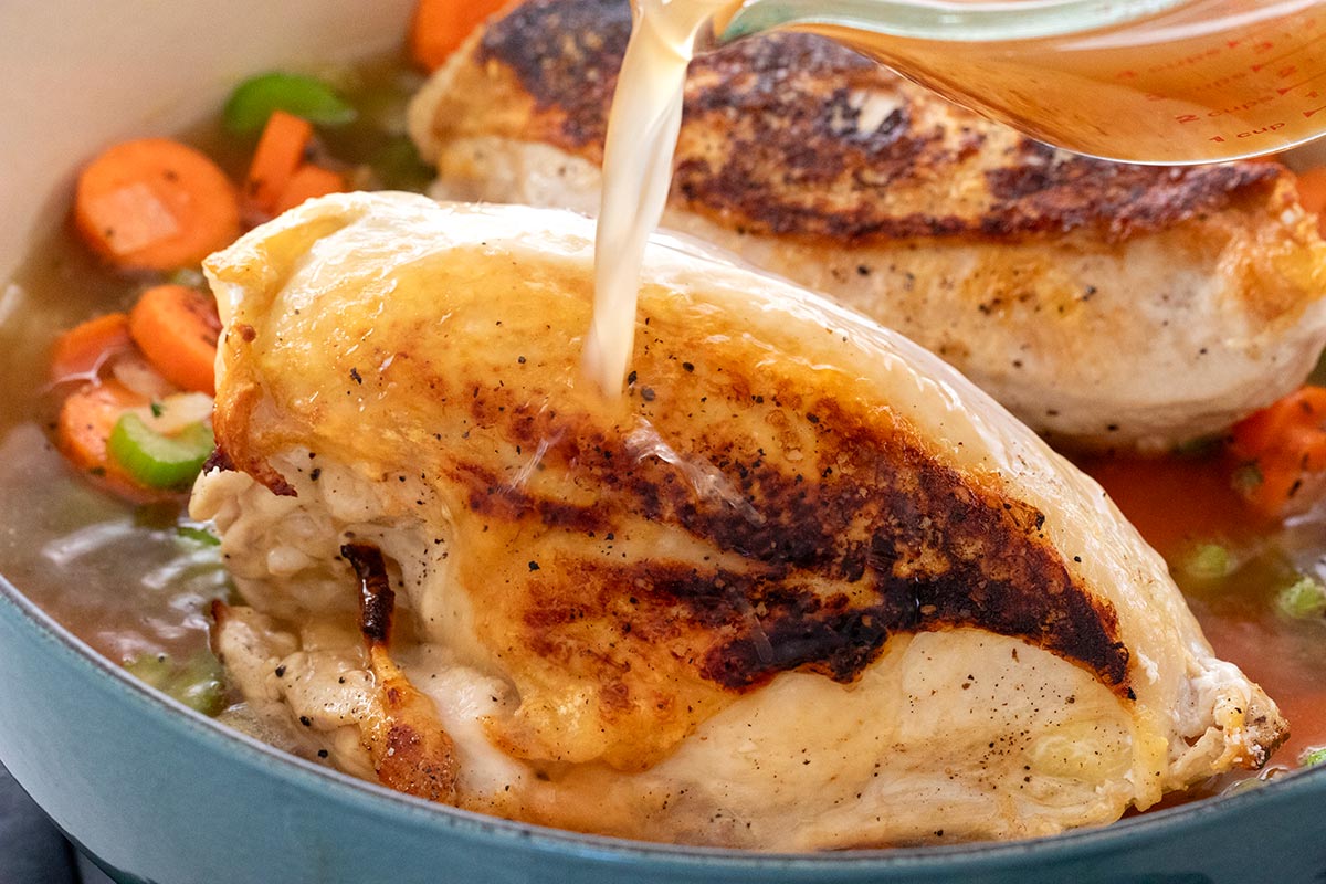 Pouring chicken stock into the pot to simmer the soup.