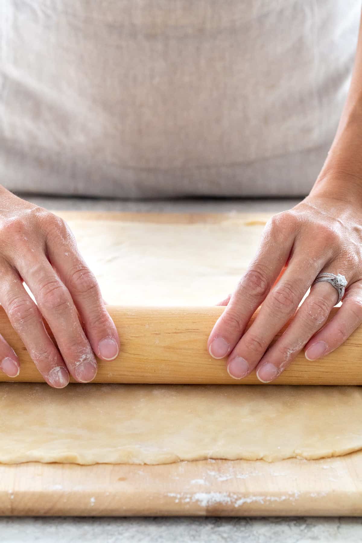 Person rolling a piece of dough with a rolling pin.