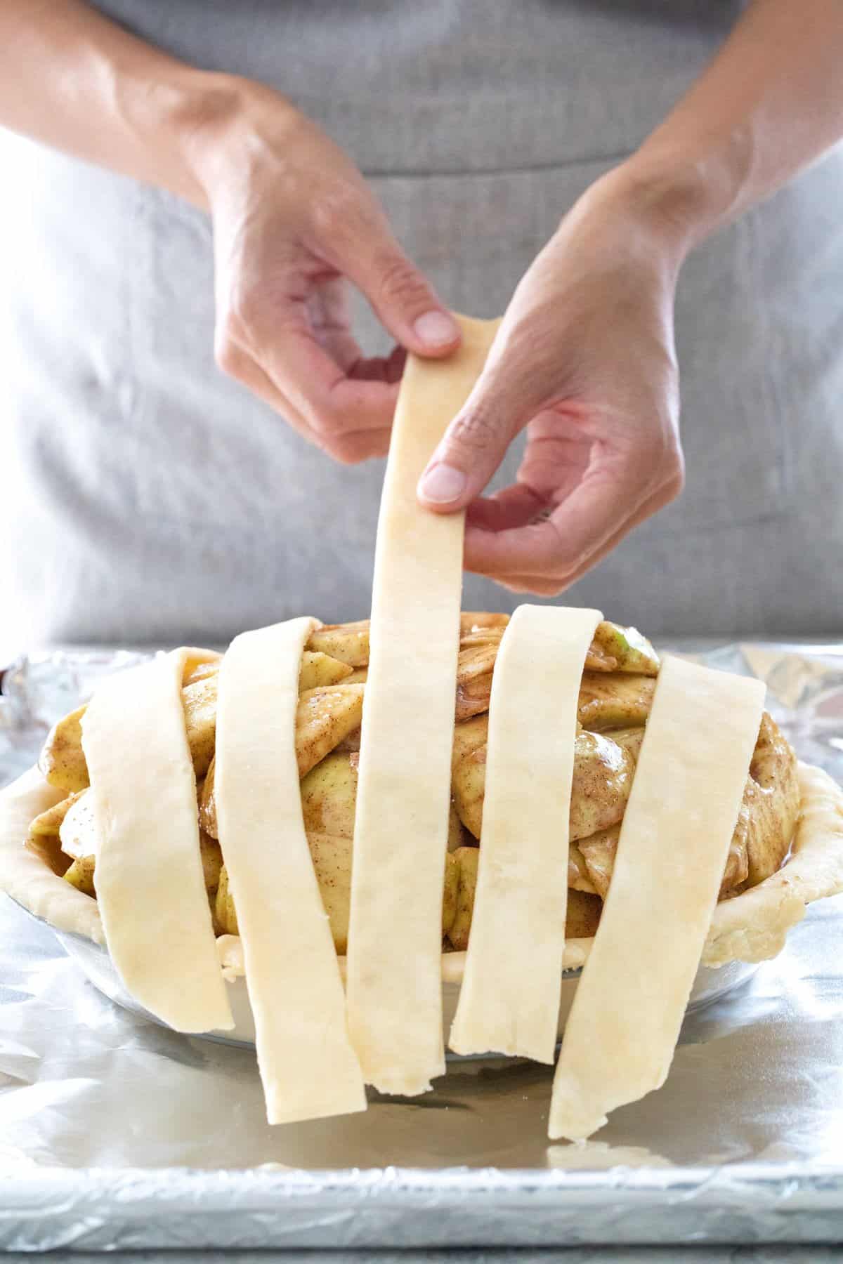 Laying five strips of dough over a pie.