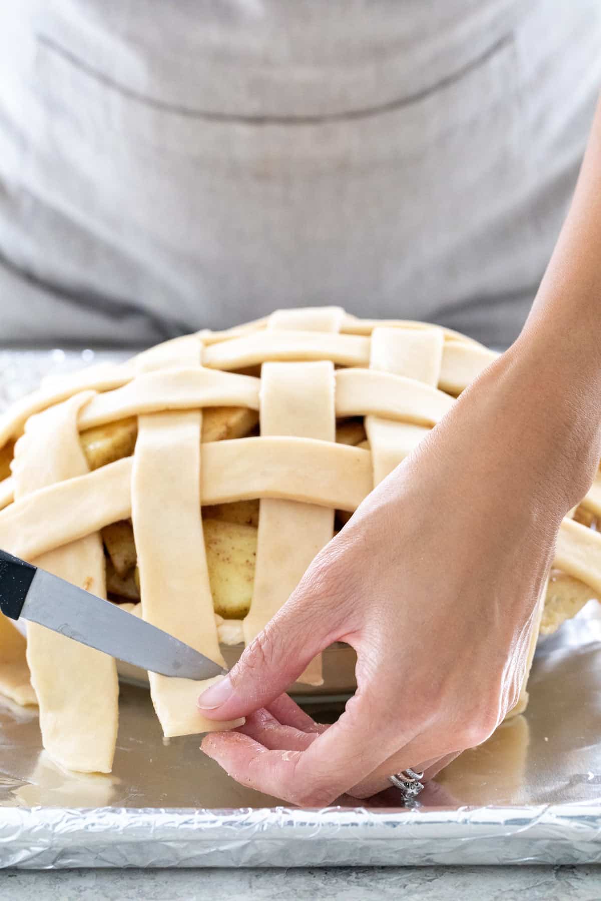 Knife cutting extra dough around a pie.