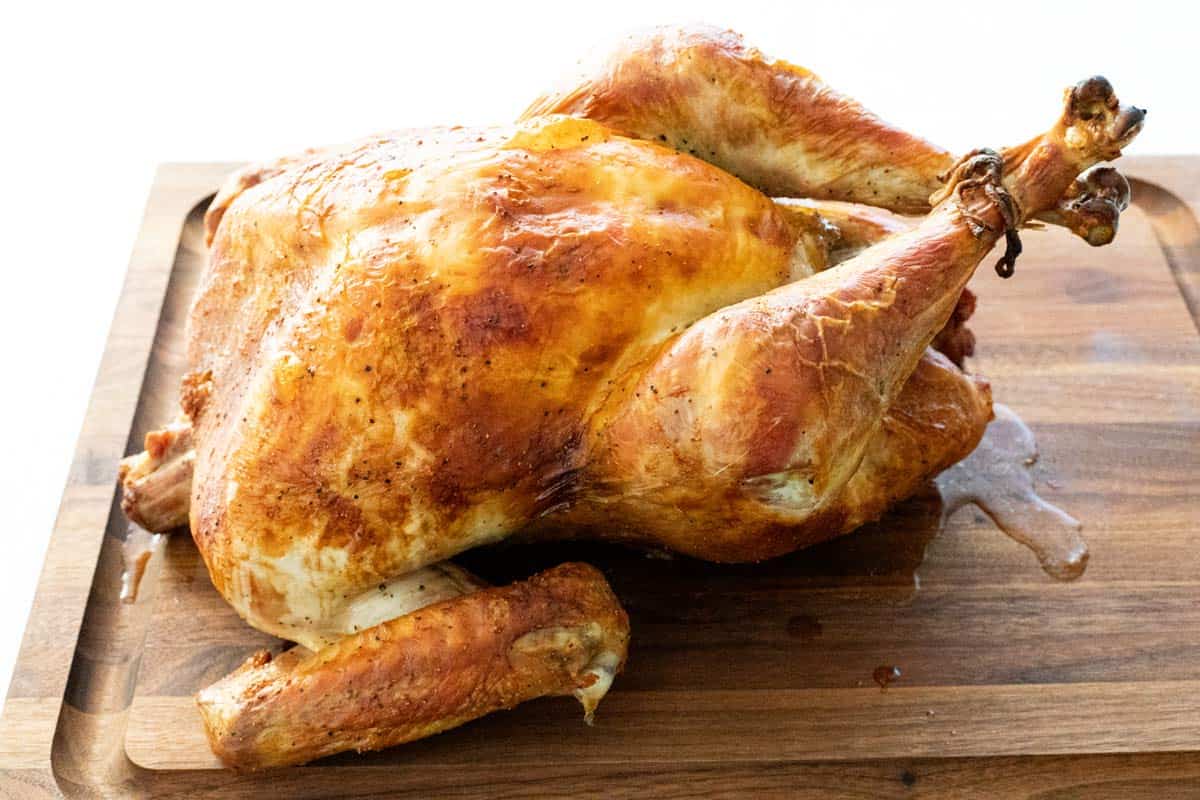Roast turkey resting on a wooden cutting board before carving.