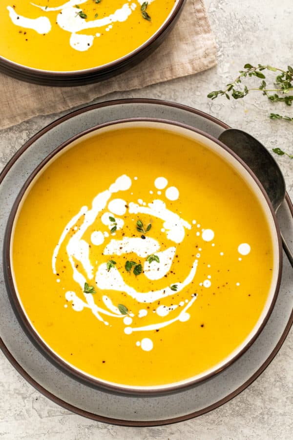 Top down view of a bowl of butternut squash soup with spots of cream.