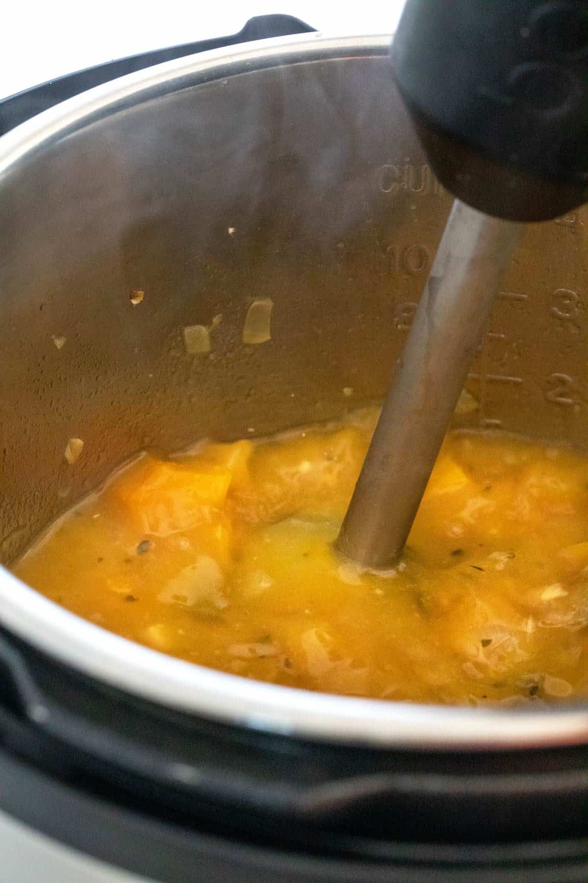 Hand immersion blender breaking down ingredients into a fine puree.
