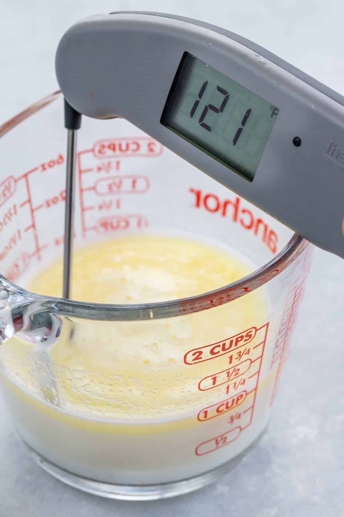 Checking the liquid butter and milk temperature with a thermometer.