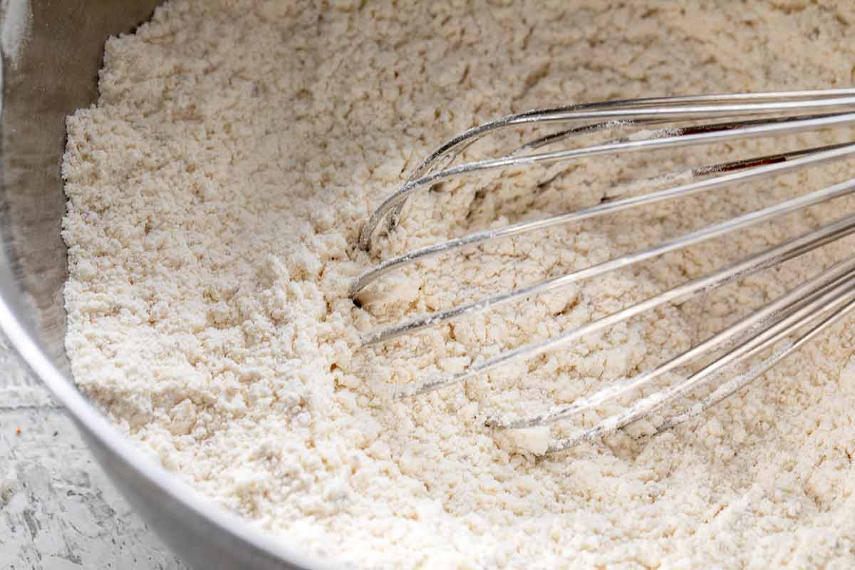 Bowl of flour and baking powder being mixed with a whisk.