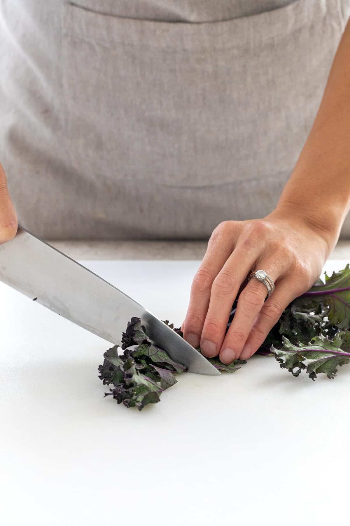 Knife cutting kale into smaller pieces.