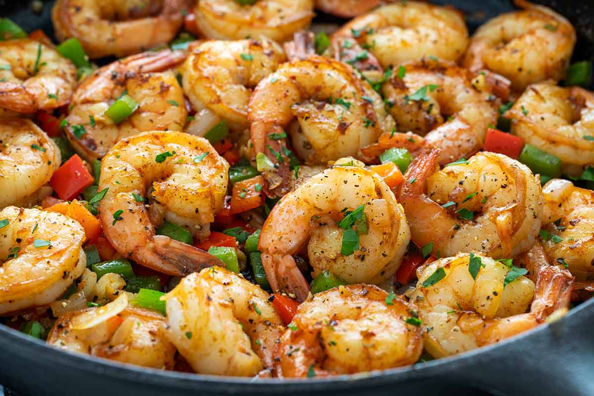 Shrimp with cajun spices in a pan with bell peppers.