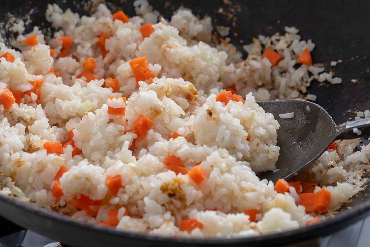 Chopped carrots, onions, and ginger mixed in a pot of white rice.