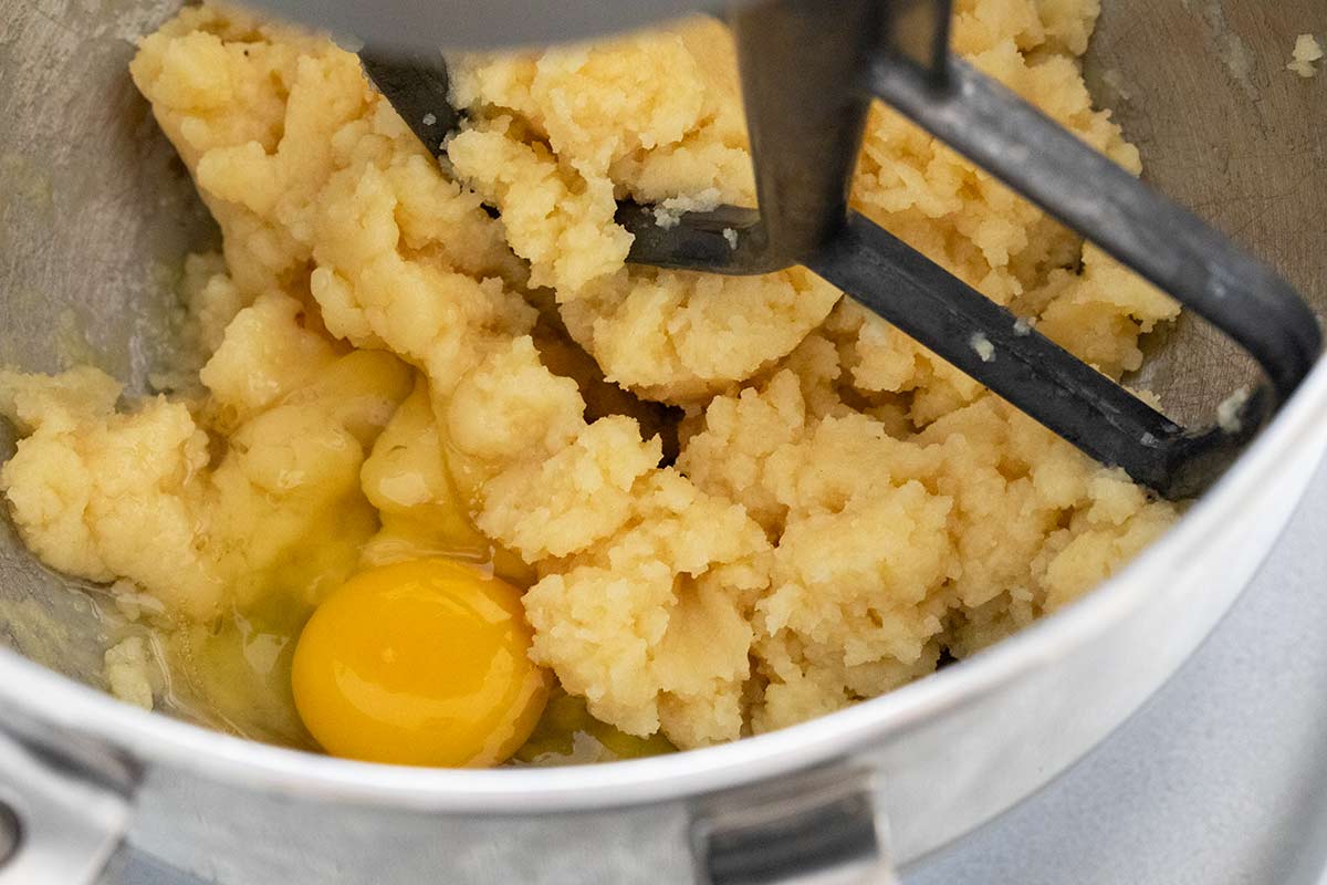 Puff pastry dough being mixed in a stand mixer with eggs.