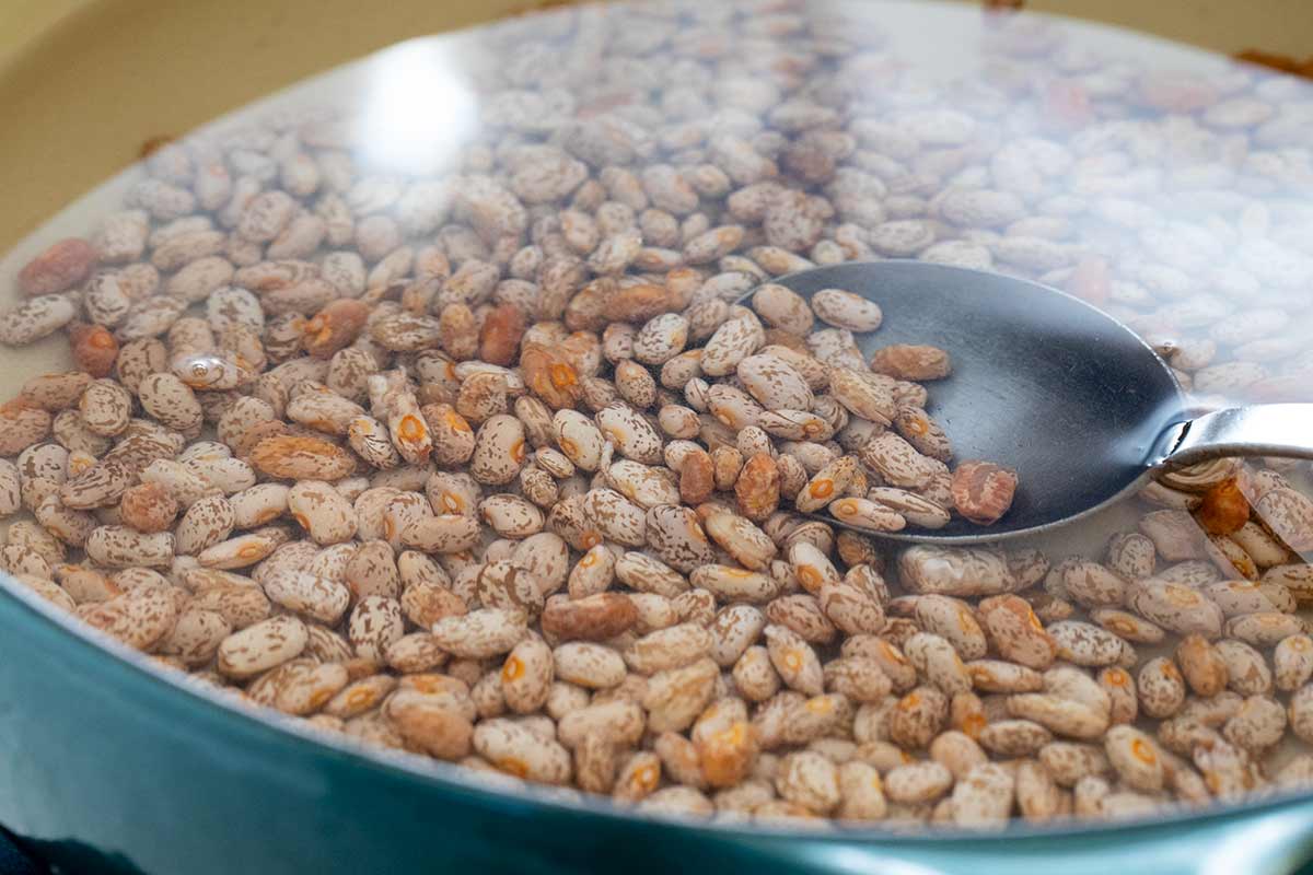 Pinto beans submerged in a large pot of water.